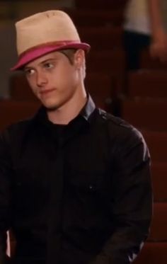 a young man wearing a black shirt and a pink hat in front of some stairs