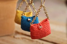 three crocheted purses are hanging from chains