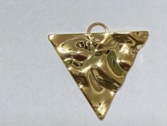 a gold triangle shaped pendant on a white background