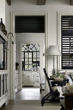 a living room filled with furniture and windows covered in shuttered glass shades on top of them