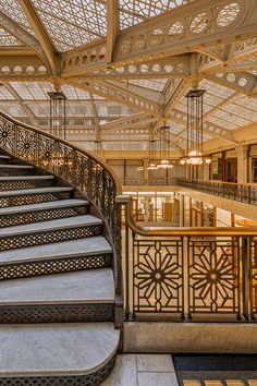 an ornate staircase with wrought iron railings and chandeliers in a large building