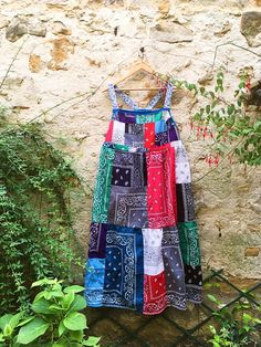 a multicolored dress hanging up against a stone wall