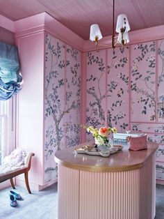 a room with pink walls and floral wallpaper on the walls, along with an island