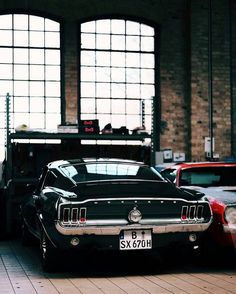 an old car is parked in front of two large windows