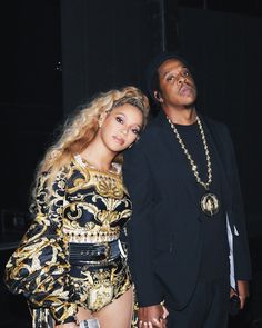 two people standing next to each other in front of a black backdrop with gold accents