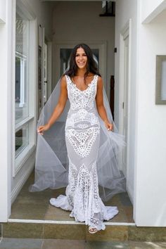 a woman in a white wedding dress is standing on the stairs with her veil over her head