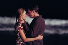 black and white photograph of a couple embracing each other on the beach at night time