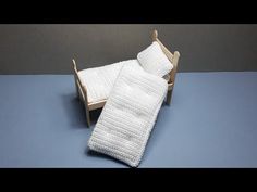 a crocheted white blanket sitting on top of a wooden chair next to a pillow