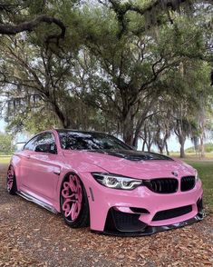 a pink car parked in front of some trees