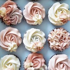 twelve cupcakes with pink and white frosting on them are arranged in a box