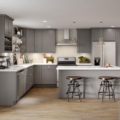 a large kitchen with gray cabinets and white counter tops, two stools in front of the island