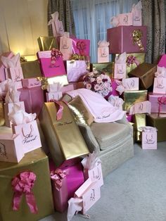 a pile of pink and gold gift boxes sitting on top of a floor next to a window