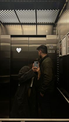 a man standing in front of an elevator holding a cell phone