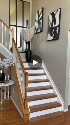 a staircase with white railing and wooden handrails in front of pictures on the wall