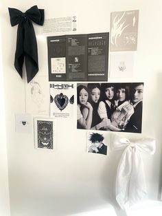 a white wall with pictures, posters and a bow hanging on it's side