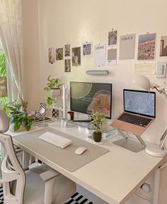 a desk with a laptop, monitor and keyboard on it in front of a window