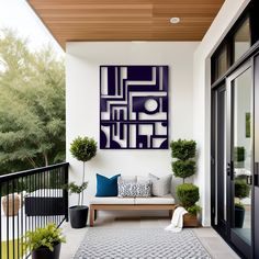 an outdoor living area with potted plants and artwork on the wall