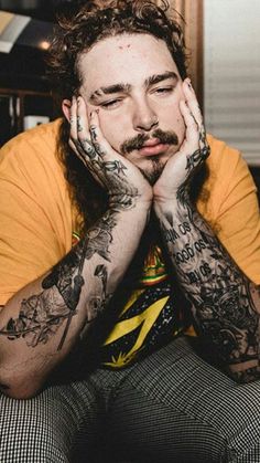 a man with tattoos on his arms and hands sitting in front of a computer desk