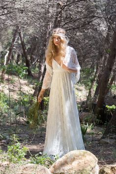 a woman in a white dress is walking through the woods