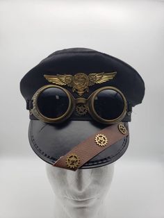 Black police-style steampunk hat with leather and gold gear trim, aviator wings, and goggles attached. One size. 24 1/2 in SHOP POLICIES: Orders placed Monday-Friday generally ship next day. Orders placed Saturday/Sunday ship the following Tuesday. Cancellations are permitted before an item ships. Please note that we do not accept returns. Steampunk Police, Aviator Aesthetic, Steampunk Googles, Steampunk Futuristic, Hat With Goggles, Black Steampunk, Steampunk Items, Police Hat, Steampunk Ideas