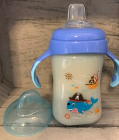 a blue and white sippy cup sitting next to an empty glass bowl on a wooden table