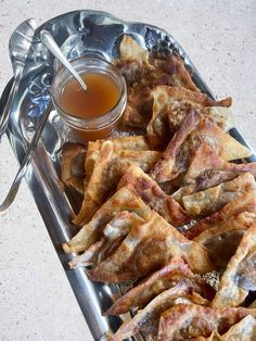 some food is sitting on a silver tray with a spoon and honey in the bowl