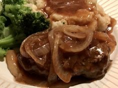 a plate with meat and gravy, broccoli and mashed potatoes