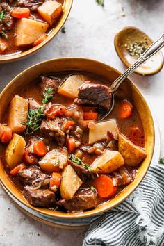 two bowls of beef stew with carrots and potatoes