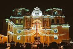 people standing in front of a large building with christmas lights on it