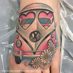 a person's foot with a pink and white vw bus tattoo on it