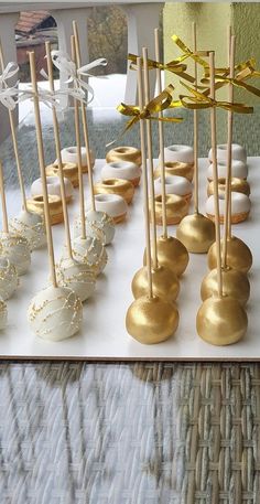 there are many desserts on the table with gold and white frosted cake pops