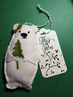 a white stuffed bear with a christmas tree on it's back next to a tag that says, this is for you