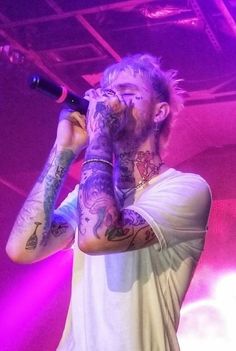 a man with tattoos singing into a microphone