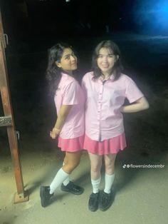 two girls in pink dresses standing next to each other