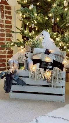 a christmas tree is decorated with white and black presents on a wooden crate in front of a brick wall