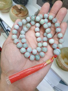 54 Jade beads handcrafted Japa Mala / Necklace; 10 mm bead size, in mix shades of glossy light green, strung using red string with each bead separated by a knot. Head bead / Guru bead is also Jade, 13.5 mm size and marbled, light bluish green color. All Jade components are Type A natural Jadeite (non-bleached, non-dyed, non-treated materials). Tassle, 3.5 inches length, consists of red and gold colored threads. Whole necklace is 26 inch length and weighs 92 grams. Meditation Beads, Buddhist Prayer, Bluish Green, Dragon Pendant, Mala Necklace, Jade Beads, Prayer Beads, Type A, Red And Gold