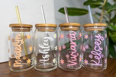 three glass jars with straws and flowers painted on the lids are sitting on a table