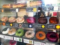 an assortment of doughnuts on display in a bakery