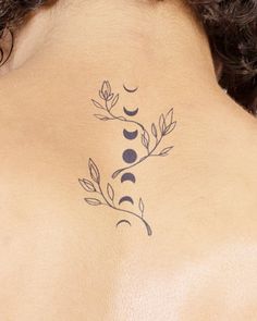 the back of a woman's neck with a tattoo on her left shoulder and leaves