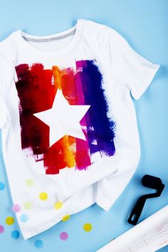 a t - shirt with a star painted on it next to scissors and confetti