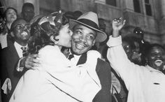 an old black and white photo of a man kissing a woman in front of a crowd