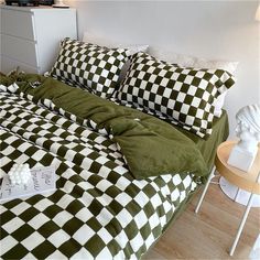 a green and white checkered comforter on a bed with two pillow cases next to a night stand