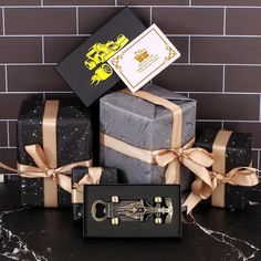 three presents are stacked on top of each other with ribbon around them and wrapped in black paper