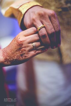 the bride and groom are holding hands with their wedding rings on their fingers as they hold each other's hand