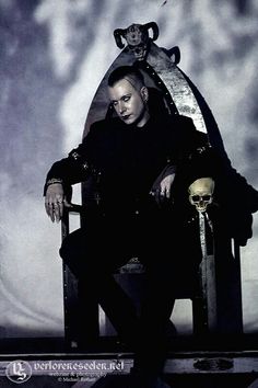 a man sitting on top of a chair next to a skull