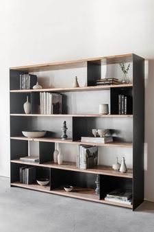 a book shelf with many books on it in an empty room next to a wall