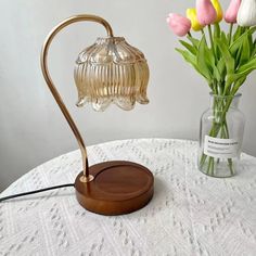 a table with flowers and a lamp on top of it next to a vase filled with tulips