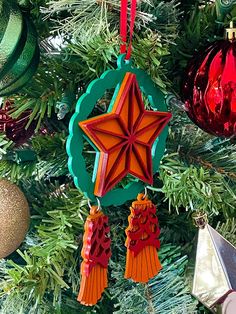 an ornament hanging from the top of a christmas tree with ornaments around it