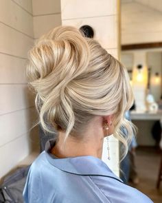 a woman with blonde hair in a bun updo and wearing a blue top is looking off to the side