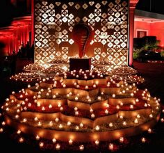 lighted candles are arranged on the ground in front of a wall with an intricate design